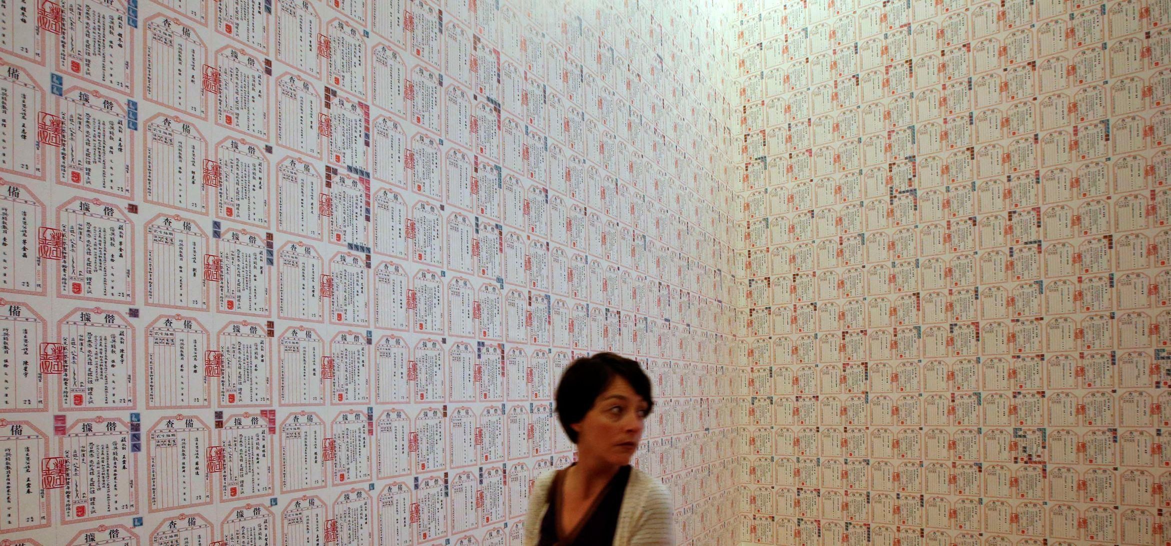 Woman walks next to installation &quot;IOU&quot; by Chinese artist Ai Weiwei during a media preview of the exhibition 'Evidence' at the Martin-Gropius Bau in Berlin