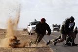 Libyjský rebel utíká před šrapnelem Kaddáfího armády nedaleko města Bin Jawad. Snímek byl pořízen 6. března 2011.