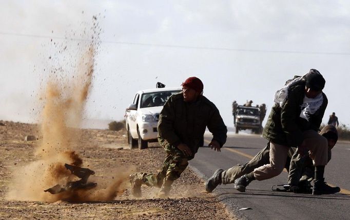 Libyjský rebel utíká před šrapnelem Kaddáfího armády nedaleko města Bin Jawad. Snímek byl pořízen 6. března 2011.