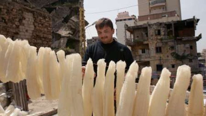 Muž suší mořské houby mezi chátrajícími domy v Bejrútu.