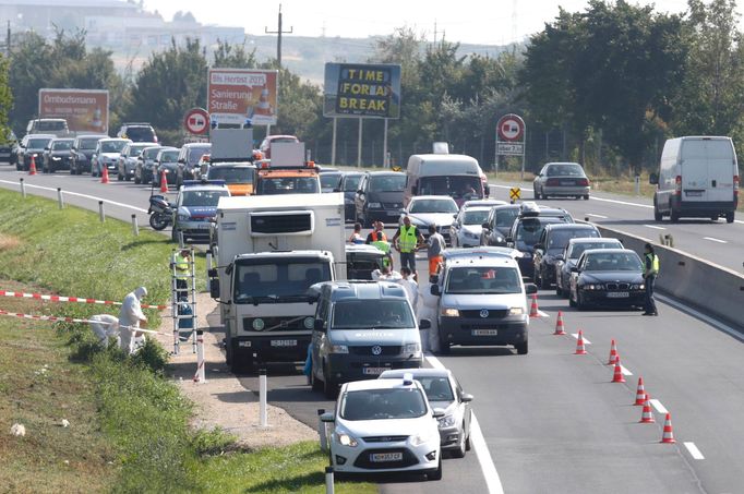 Forenzní experti zkoumají odstavený vůz na dálnici A4, v němž byly nalezeny ostatky desítek uprchlíků.