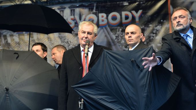 Prezident Miloš Zeman na pražském Albertově. Před létajícími vejci ho chránily deštníky.