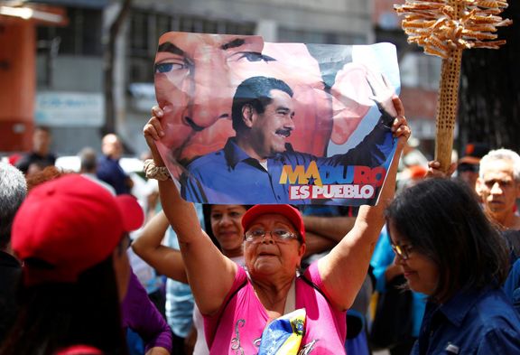 Podporovatelka venezuelské vlády drží plakát s prezidentem Nicolásem Madurem a jeho předchůdcem Hugem Chávezem.