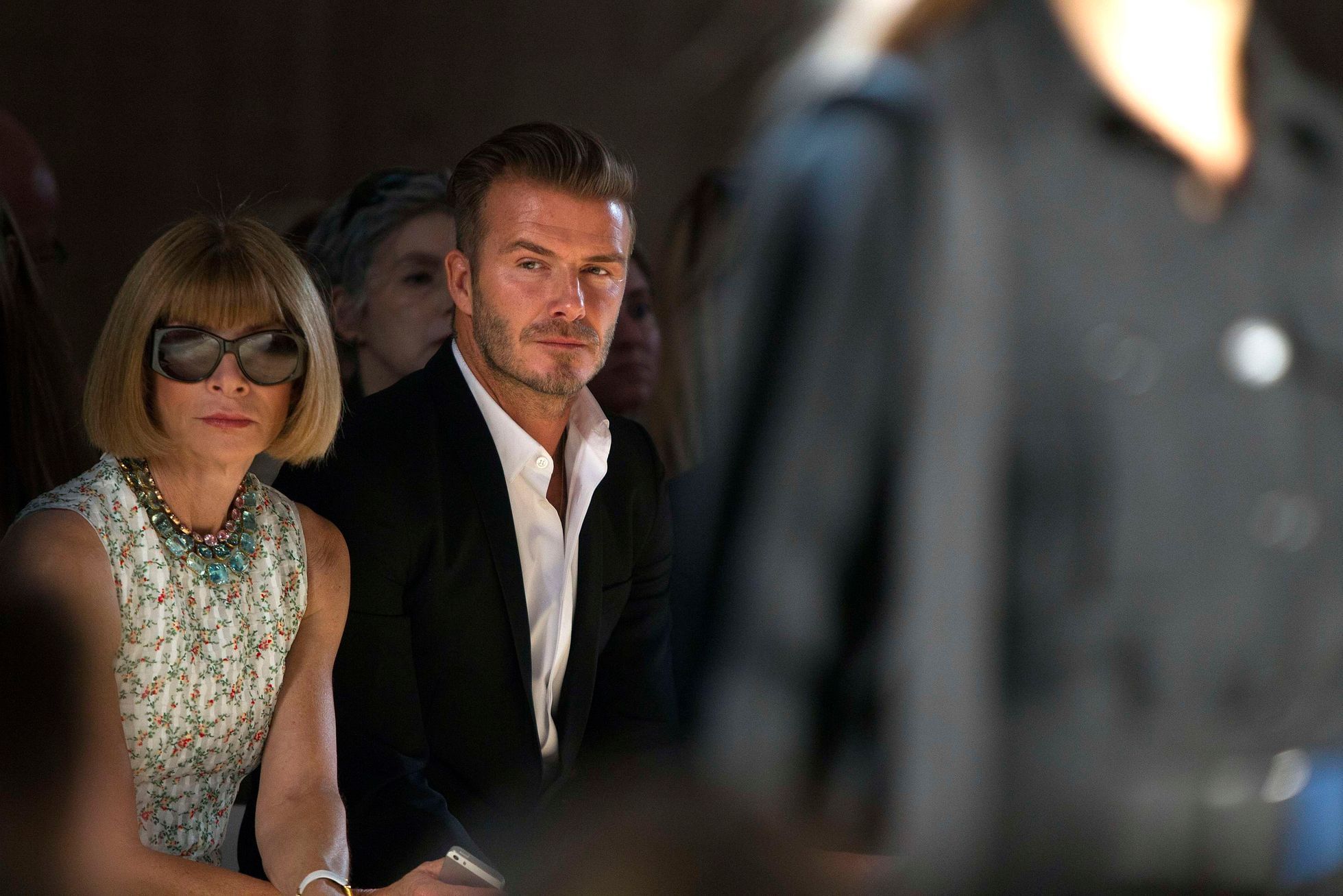Vogue editor Anna Wintour (L) and David Beckham watch as a model presents a creation during the Victoria Beckham Spring/Summer 2015 collection during New York Fashion Week in the Manhattan borough of