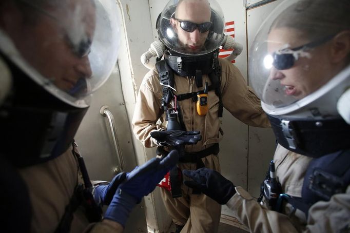 Matt Cross (L), rover engineer, Hans van Ot Woud (C), mapping researcher and health and safety officer, and Melissa Battler, geologist and commander of Crew 125 EuroMoonMars B mission of the Mars Desert Research Station (MDRS), wait in an airlock in their simulated spacesuits before venturing out to collect geologic samples in the Utah desert March 2, 2013. The MDRS aims to investigate the feasibility of a human exploration of Mars and uses the Utah desert's Mars-like terrain to simulate working conditions on the red planet. Scientists, students and enthusiasts work together developing field tactics and studying the terrain. All outdoor exploration is done wearing simulated spacesuits and carrying air supply packs and crews live together in a small communication base with limited amounts of electricity, food, oxygen and water. Everything needed to survive must be produced, fixed and replaced on site. Picture taken March 2, 2013. REUTERS/Jim Urquhart (UNITED STATES - Tags: SCIENCE TECHNOLOGY SOCIETY ENVIRONMENT) ATTENTION EDITORS: PICTURE 11 OF 31 FOR PACKAGE 'MARS IN THE DESERT' SEARCH 'JIM MARS' FOR ALL IMAGES Published: Bře. 11, 2013, 2:04 odp.