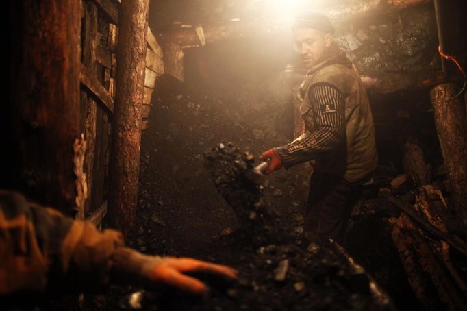 An illegal miner shovels coal at a mine in the village of Stranjani, near Zenica, December 11, 2012. There are about 20 illegal mines in the area, where Bosnians dig for coal with bare hands and use primitive tools such as bathtubs to transport the coal. They sell one bag of coal for 3 euro. Local people are buying this coal because is duoble cheaper then in the city mine. REUTERS/Dado Ruvic (BOSNIA AND HERZEGOVINA - Tags: BUSINESS ENERGY CRIME LAW SOCIETY) BOSNIA AND HERZEGOVINA OUT. NO COMMERCIAL OR EDITORIAL SALES IN BOSNIA AND HERZEGOVINA Published: Pro. 11, 2012, 4:43 odp.