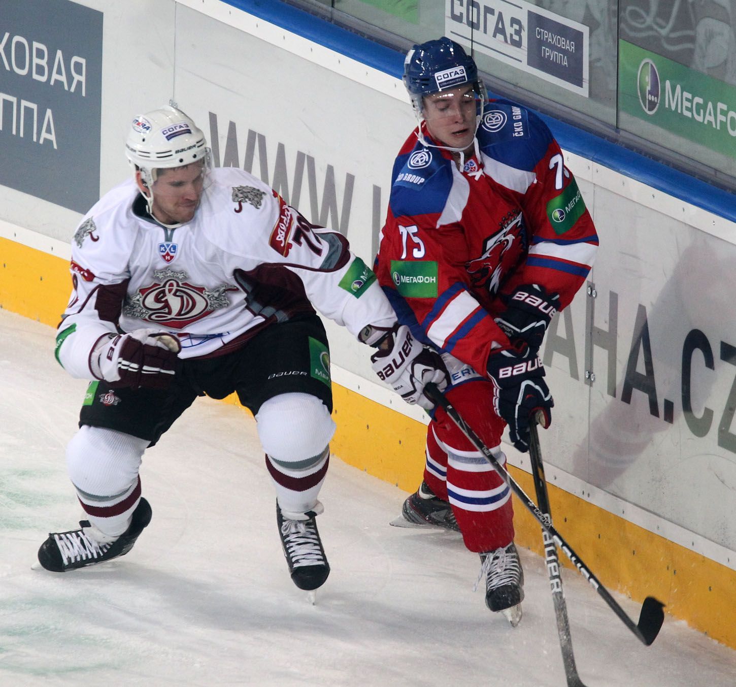 Hokejista Vitalij Karamnov (vpravo) uniká před Gunarsem Skvorcovsem v utkání KHL 2012/13 mezi Lvem Praha s Dinamem Riga .