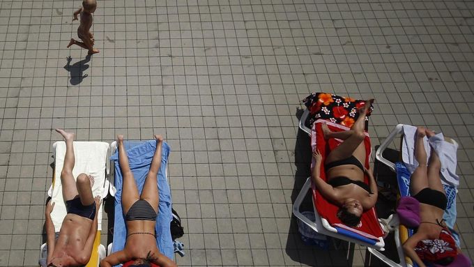 People sunbath as a child runs past them at the public swimming pool Kongressbad in Vienna June 30, 2012. Temperatures will rise up to 37 degrees Celsius (98.6 Fahrenheit) in Austria in the next days, Austria's national weather service agency ZAMG reported. REUTERS/Lisi Niesner (AUSTRIA - Tags: ENVIRONMENT TPX IMAGES OF THE DAY) Published: Čer. 30, 2012, 2:24 odp.
