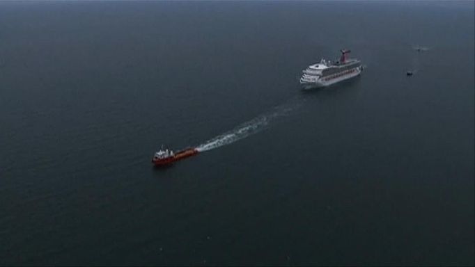 The cruise ship Carnival Triumph cruise ship is towed in this video frame grab from NBC News taken off the coast of Alabama, February 14, 2013. Three tugboats were hauling the disabled cruise ship Carnival Triumph cruise ship slowly into port in Mobile, Alabama, on Thursday where its arrival with more than 4,220 people aboard was expected later in the day, authorities said. REUTERS/NBC News/Handout (UNITED STATES - Tags: BUSINESS SOCIETY MARITIME TRANSPORT TRAVEL HEALTH) NO SALES. NO ARCHIVES. FOR EDITORIAL USE ONLY. NOT FOR SALE FOR MARKETING OR ADVERTISING CAMPAIGNS. THIS IMAGE HAS BEEN SUPPLIED BY A THIRD PARTY. IT IS DISTRIBUTED, EXACTLY AS RECEIVED BY REUTERS, AS A SERVICE TO CLIENTS Published: Úno. 14, 2013, 7:10 odp.