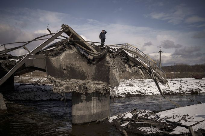 Muž hledí do dáli z trosek zničeného mostu v ukrajinském městě Irpiň. 8. 3. 2022