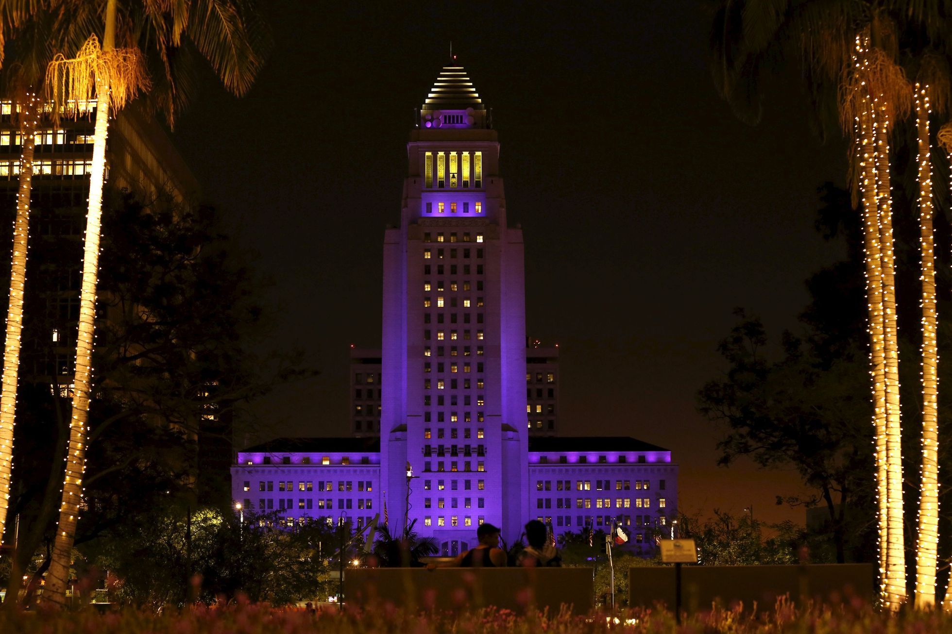 People watch as City Hall is illuminated in purple in remembrance of the late singer Prince in Downtown Los Angeles