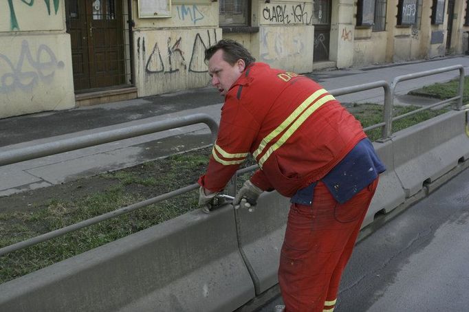 Dělníci začínají demontovat betonové zábrany. Potom je posunou o několik metrů dál do ulice.