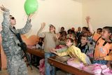 Znovuotevřená škola ve městě Latifiya. Americký voják na návštěvě si hraje s balónkem.