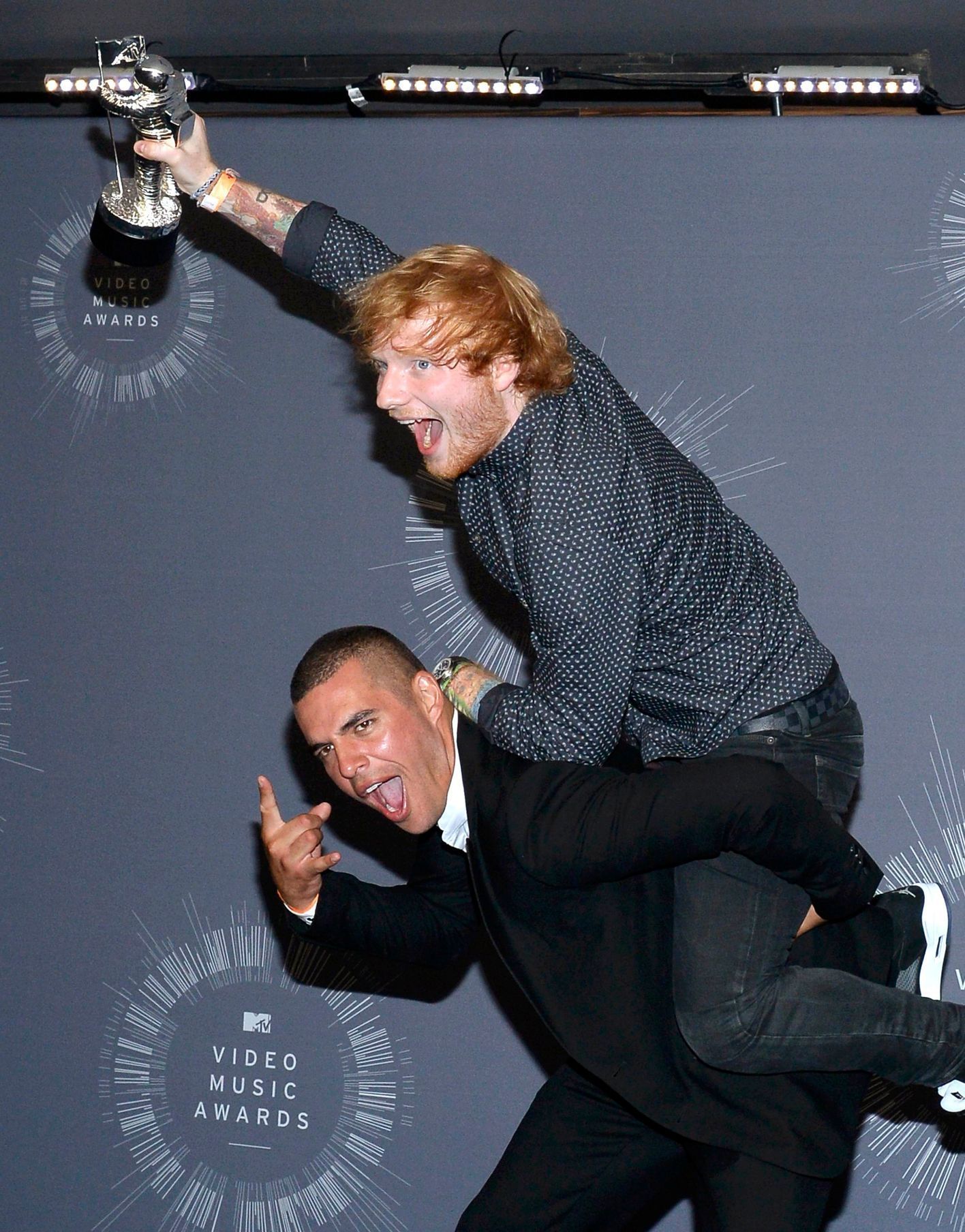 Singer Ed Sheeran jumps onto the back of director Emil Nava backstage after winning the award for best male video for &quot;Sing&quot; backstage during the 2014 MTV Video Music Awards in Inglewood