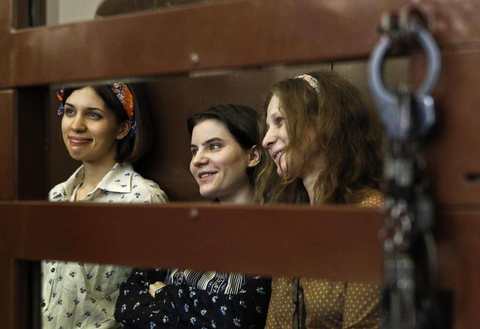 Nadezhda Tolokonnikova (L), Yekaterina Samutsevich and Maria Alyokhina (R), members of female punk band "Pussy Riot", attend their trial inside the defendents' cell in a court in Moscow August 3, 2012. President Vladimir Putin said on Thursday that three women on trial for a protest performance in Russia's main cathedral should not be judged too harshly, signaling he did not favor lengthy prison terms for the Pussy Riot band members, Russian news agencies reported. REUTERS/Maxim Shemetov (RUSSIA - Tags: POLITICS ENTERTAINMENT CIVIL UNREST CRIME LAW) Published: Srp. 3, 2012, 8:56 dop.