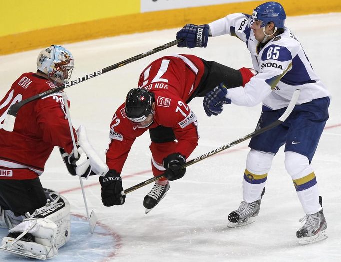 Konstantin Romanov (vpravo) před gólmanem Švýcarska Reto Berrou a Patrickem von Guntenem. Zápas skupiny A Kazachstán - Švýcarsko na MS v hokeji.