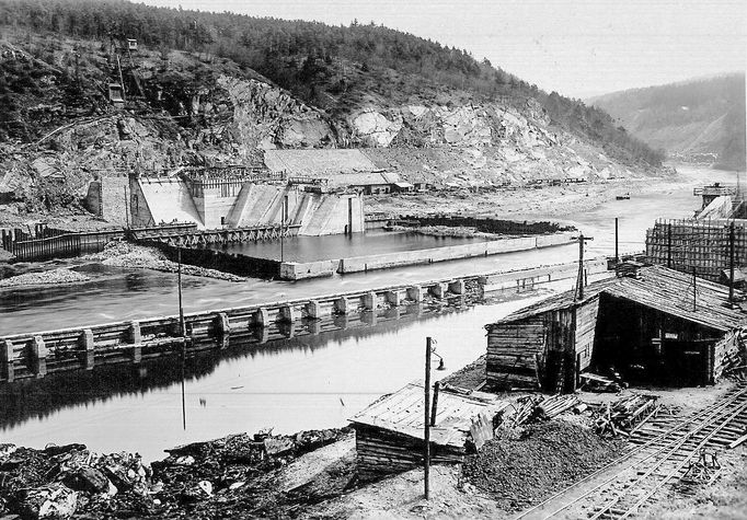 Historická fotografie zachycující výstavbu vodní nádrže Štěchovice, která probíhala mezi lety 1937 a 1944, navzdory válečným komplikacím.