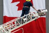 Richmondský hasič upevňuje kanadskou vlajku nad skřížené hokejové hole na požární stanici.