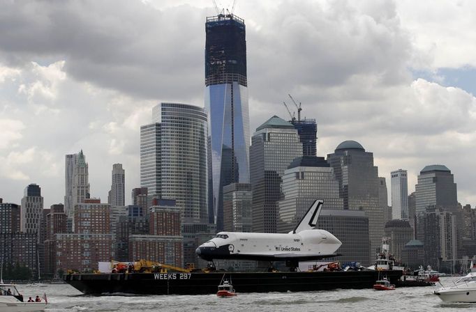 The Space Shuttle Enterprise, passes lower Manhattan and the still under construction 1 World Trade Center tower (C) as it rides on a barge in New York harbor, June 6, 2012. The Space Shuttle Enterprise was being moved up the Hudson River to be placed at the Intrepid Sea, Air and Space Museum. REUTERS/Mike Segar (UNITED STATES - Tags: TRANSPORT SCIENCE TECHNOLOGY) Published: Čer. 6, 2012, 5:15 odp.