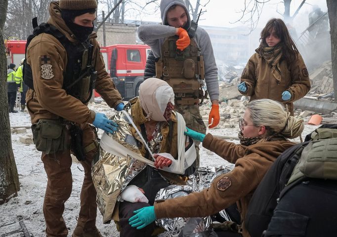 Záchranáři ošetřují ženu, zraněnou při úterním ruském raketovém útoku na Charkov.