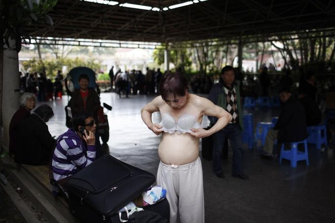 Xiao Cao, a 57-year-old gay man, puts on a bra before his performance at Manxi park in Shanghai April 8, 2012. China's gay community has long been on the edges of society but it is gradually becoming more accepted. Cao, who is an unemployed drag queen, is one whose life lifts the curtain on a less romanticised view of Chinese homosexuals. Living in an eight-square-metre apartment behind a public toilet and with a monthly income of 500 yuan ($79) from social insurance, he passes his days dancing in public and spending time with friends at gay clubs. Picture taken April 8, 2012. REUTERS/Aly Song (CHINA - Tags: SOCIETY) CHINA OUT. NO COMMERCIAL OR EDITORIAL SALES IN CHINA. ATTENTION EDITORS PICTURE 18 OF 28 OF PACKAGE 'GAY AND OUT IN CHINA' TO FIND ALL IMAGES SEARCH 'GAY OUT CHINA' Published: Čer. 1, 2012, 12:40 dop.