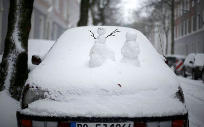 Sněhuláčci na zasněženém autě v Dortmundu.