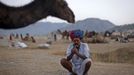 A camel herder lights a cigarette near a camel at Pushkar Fair in the desert Indian state of Rajasthan November 23, 2012. Many international and domestic tourists throng to Pushkar to witness one of the most colourful and popular fairs in India. Thousands of animals, mainly camels, are brought to the fair to be sold and traded. REUTERS/Danish Siddiqui (INDIA - Tags: SOCIETY ANIMALS) Published: Lis. 23, 2012, 5:15 odp.