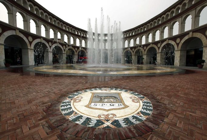 An emblem decorates the pavement next to a fountain inside a building that looks like a Roman Coliseum at the Florentia Village in the district of Wuqing, located on the outskirts of the city of Tianjin June 13, 2012. The shopping center, which covers an area of some 200,000 square meters, was constructed on a former corn field at an estimated cost of US$220 million and copies old Italian-style architecture with Florentine arcades, a grand canal, bridges, and a Coliseum-like building. REUTERS/David Gray (CHINA - Tags: SOCIETY BUSINESS) Published: Čer. 13, 2012, 5:17 odp.