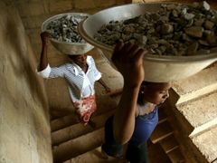 Mladé ženy pracující na stavbách musejí tahat těžké mísy s kamením do schodů.