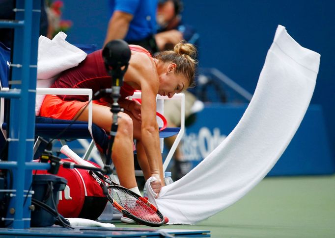 Simona Halep of Romania reacts during a break in play after losing a game to Flavia Pennetta of Italy in their women's singles semi-final match at the U.S. Open Champions