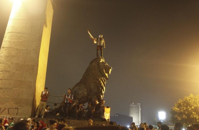 An anti-Mursi protester wearing a Guy Fawkes mask celebrates on top of a lion statue near Tahrir square after the announcement of the removal from office of Egypt's deposed President Mohamed Mursi in Cairo, July 4, 2013. Mursi, toppled by the military on Wednesday, is being held by the authorities, a Muslim Brotherhood spokesman and a security official said on Thursday. REUTERS/Asmaa Waguih (EGYPT - Tags: POLITICS CIVIL UNREST) Published: Čec. 4, 2013, 12:43 dop.