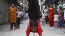 People watch as Drumpal Choudhary, 11, a street performer, performs his tricks on a street in Kathmandu August 15, 2012. Drumpal and his siblings Shivani and Gchan, who came to Kathmandu from India 5 years ago, earn their living by performing tricks on the streets of Kathmandu. According to Drumpal they earn around $10 a day by performing tricks, which is not enough to feed their 10-member family living together in a small hut without a proper toilet or any basic needs. REUTERS/Navesh Chitrakar (NEPAL - Tags: SOCIETY POVERTY IMMIGRATION) Published: Srp. 15, 2012, 4:36 odp.