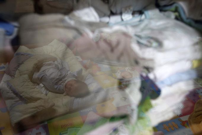 An abandoned baby is seen reflected in a closet after it was found in a "baby box" at Joosarang church in Seoul September 19, 2012. Pastor Lee Jong-rak who runs a "baby box" where mothers can leave unwanted infants has seen a sharp increase in the number of newborns being left there because, the pastor says, of a new law aimed protecting the rights of children. South Korea is trying to shed a reputation of being a source of babies for adoption by people abroad. It is encouraging domestic adoption and tightening up the process of a child's transfer from birth mother to adoptive parents. Picture taken September 19, 2012. REUTERS/Kim Hong-Ji (SOUTH KOREA - Tags: SOCIETY) Published: Říj. 7, 2012, 6:48 dop.