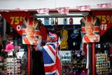 Muž zavinutý do britské vlajky věší portrét královny.