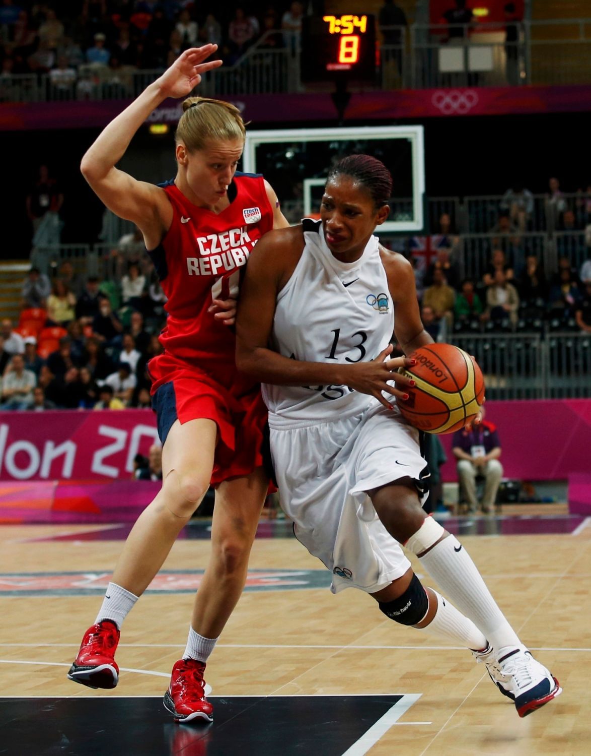 Česká basketbalistka Kateřina Elhotová blokuje Angolku Nacisselu Mauriciovou v utkání skupiny A na OH 2012 v Londýně.