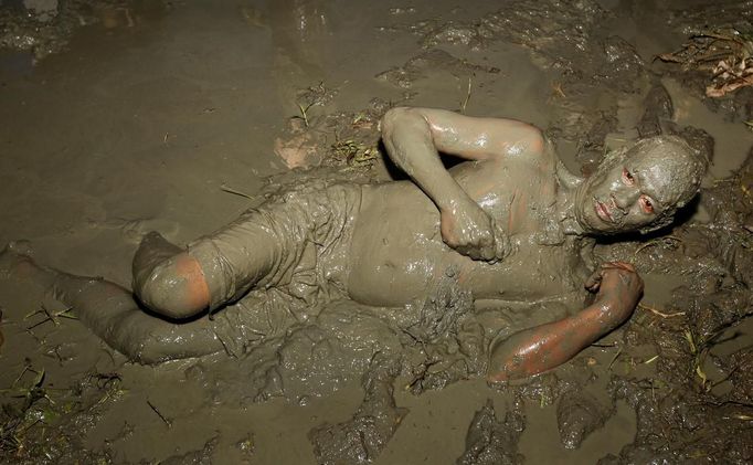 A devotee lies on his side while applying mud onto his body in a rice field during a religious ceremony celebrating the feast day of the Catholic patron Saint John the Baptist in the village of Bibiclat, Nueva Ecija, north of Manila, June 24, 2012. Hundreds of devotees took part in this annual religious tradition, which has been held in the village since 1945. REUTERS/Erik De Castro (PHILIPPINES - Tags: SOCIETY RELIGION) Published: Čer. 24, 2012, 6:10 dop.