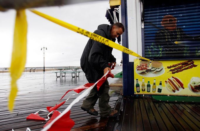 Zaměstnanec správy města New York označuje zapovězená místa řetězem vlaječek na na promenádě Coney Island.