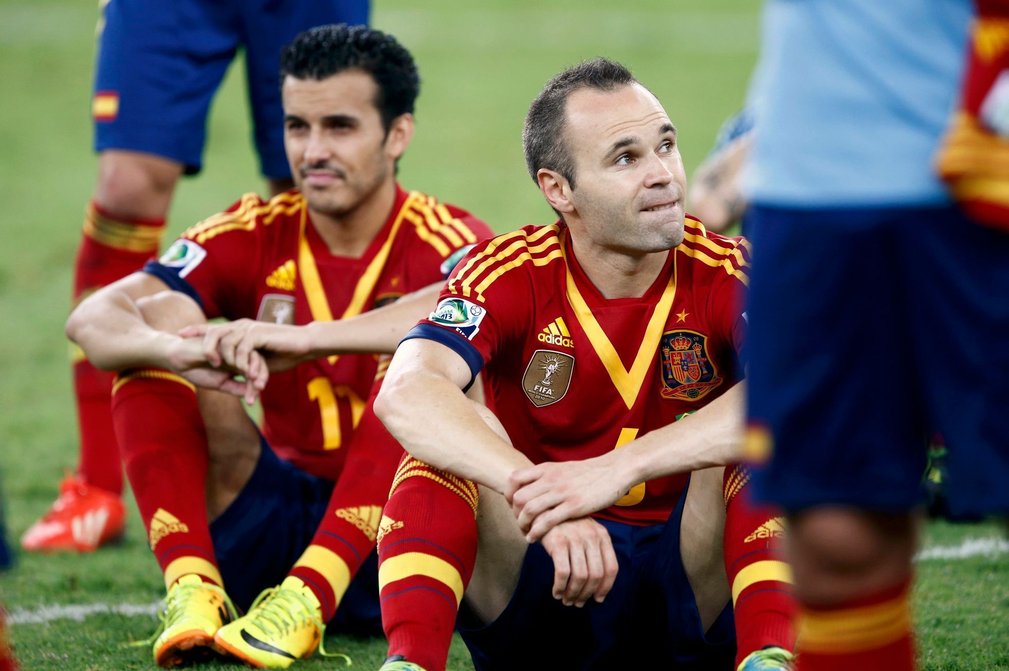 Spain's Iniesta and Pedro sit on the field after losing thei