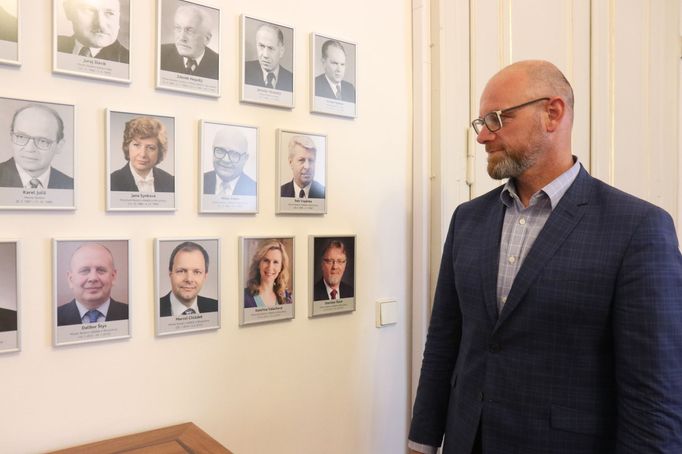 Ministr školství Robert Plaga před galerií, ve které jsou fotografie všech jeho předchůdců. Plaga je 45. ministrem školství od vzniku Československa v roce 1918