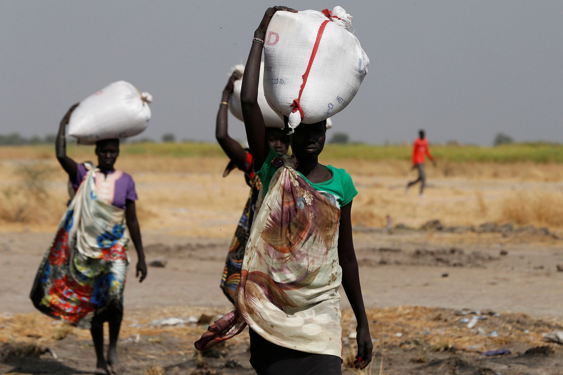 Ženy v Jižním Súdánu nesou pytle s jídlem.