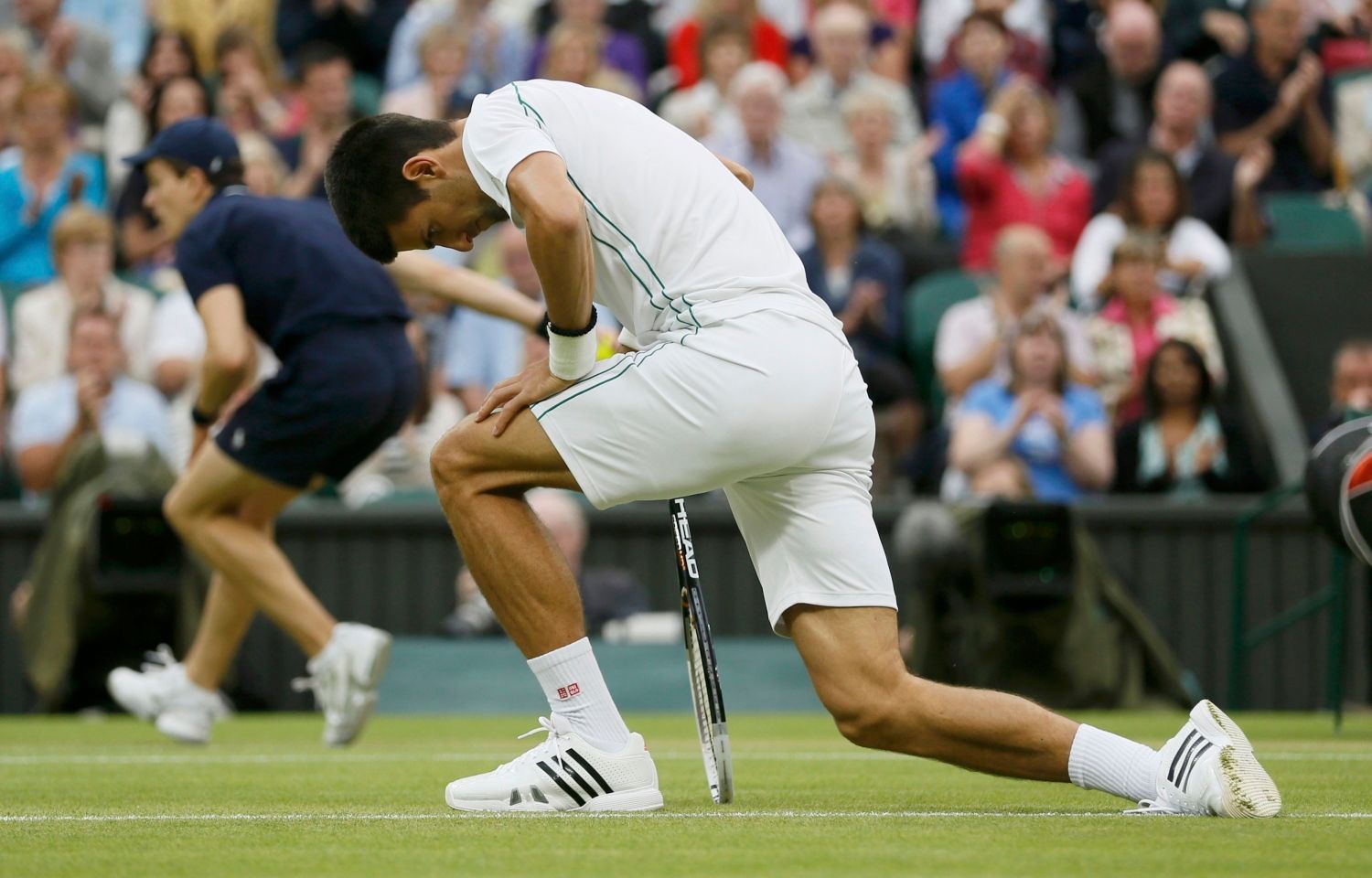 Srbský tenista Novak Djokovič po pádu v semifinálovém utkání Wimbledonu 2012 se Švýcarem Rogerem Federerem.