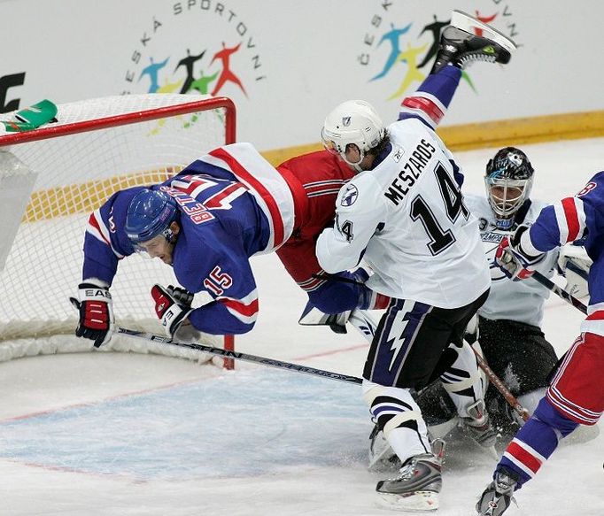 Blair Betts (vlevo) sražený Andrejem Meszarosem a Olafem Kolzigem během utkání NHL v Praze.