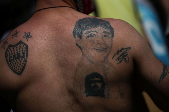 A man with a tattoo of soccer legend Diego Armando Maradona on his back poses for a picture outside the Casa Rosada presidential palace as people gather to mourn Maradona