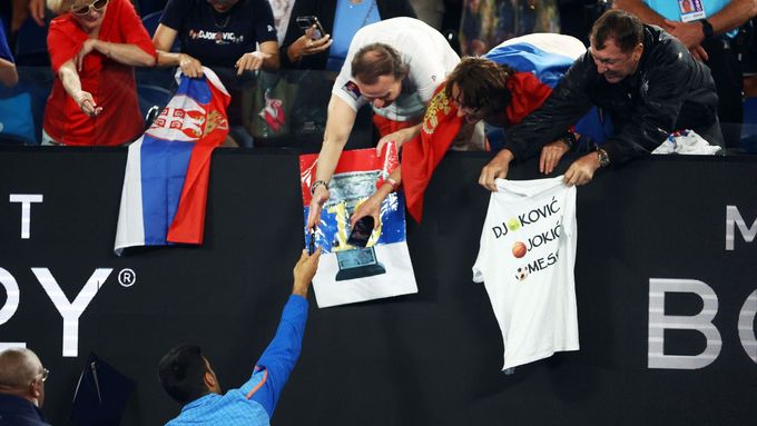 Novak Djoković se podepisuje fanouškům po výhře nad Andrejem Rubljovem. Muž napravo měl pod bundou triko se symbolem Z