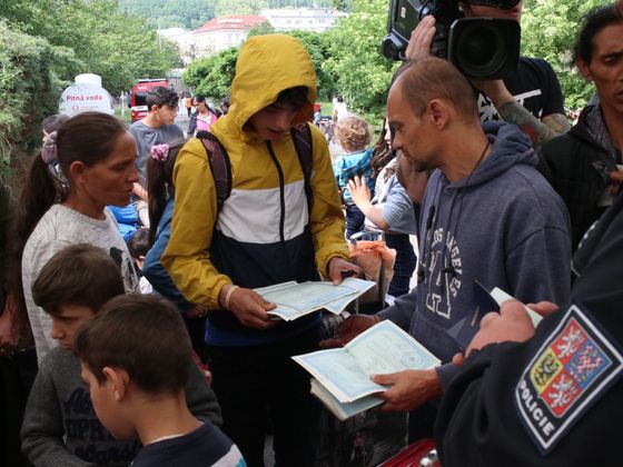 Romští uprchlíci ukazují své dokumenty. 