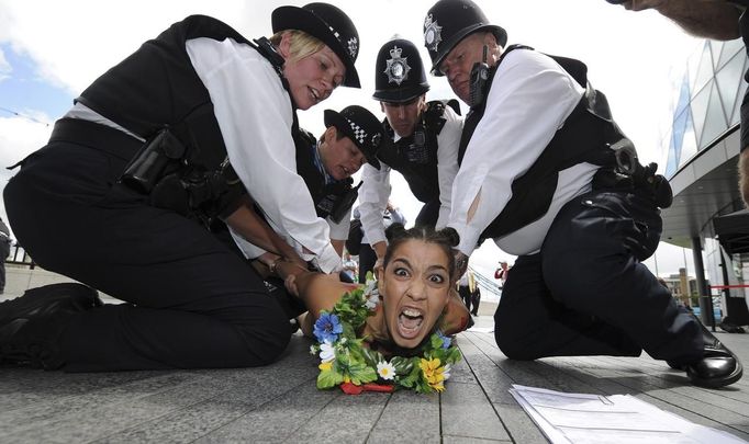 Britští policisté zatýkají obnaženou aktivistku, která v olympijském areálu protestovala proti přítomnosti týmů z islámských zemí, kde jsou u moci nedemokratické režimy.