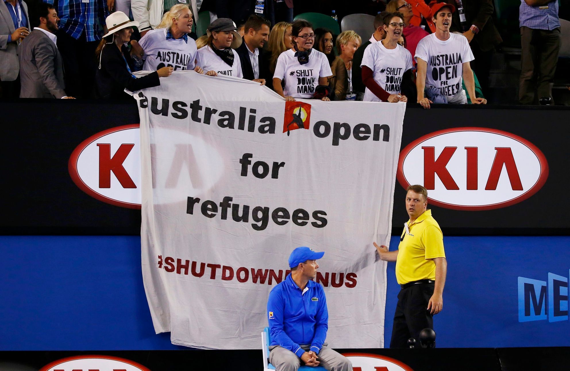 A line judge and security officer react as protesters display a banner during the men's singles final match between Djokovic of Serbia and Murray of Britain at the Australian Open 2015 tennis tourname