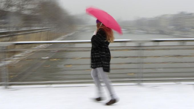 A woman holding an umbrella walks on a snow-covered bridge over the River Seine in Paris March 12, 2013 as winter weather with snow and freezing temperatures returns to northern France. REUTERS/Gonzalo Fuentes (FRANCE - Tags: ENVIRONMENT TPX IMAGES OF THE DAY) Published: Bře. 12, 2013, 3:09 odp.