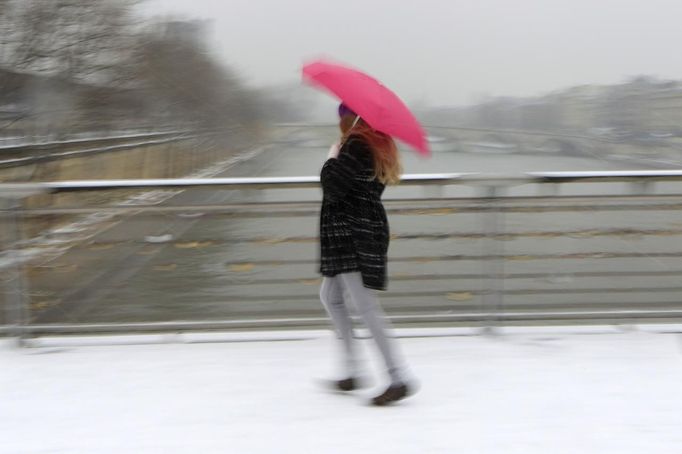 A woman holding an umbrella walks on a snow-covered bridge over the River Seine in Paris March 12, 2013 as winter weather with snow and freezing temperatures returns to northern France. REUTERS/Gonzalo Fuentes (FRANCE - Tags: ENVIRONMENT TPX IMAGES OF THE DAY) Published: Bře. 12, 2013, 3:09 odp.