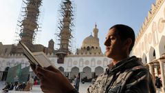 Muž čte korán před jednou z káhirských mešit